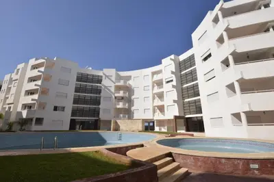 an apartment complex with a swimming pool in front of a building at Bouznika 22 in Bouznika
