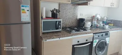 a kitchen with a microwave and a washer and dryer at appartement Shems Bouznika Premium in Bouznika