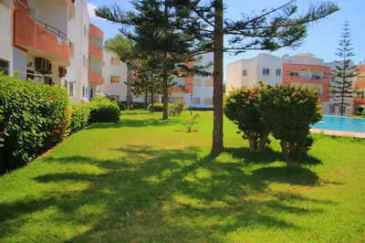 a garden with trees and bushes next to a building at Mohammedia pour les vacances in Mohammedia