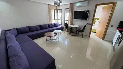 a living room with a purple couch and a table at CASA BEACH HOTEL in Sidi Rahal