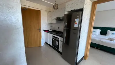 a kitchen with a black refrigerator and a bed at CASA BEACH HOTEL in Sidi Rahal