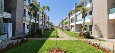 an empty courtyard of an apartment building with palm trees at Appartement neuf haut standing vue mer in Skhirat