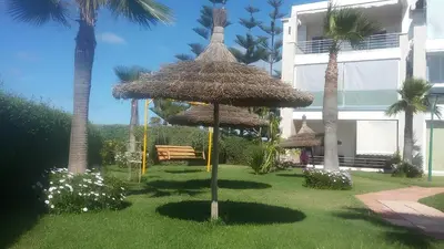 a park with a bench and a large umbrella at Appartement au Bord de la Mer in Casablanca