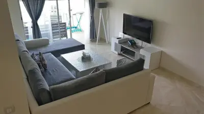 a living room with a couch and a television at Casabay Appart Vue Sur Piscine in Sidi Rahal