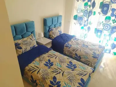 a bedroom with two beds with blue covers and a window at Casabay Appart Vue Sur Piscine in Sidi Rahal