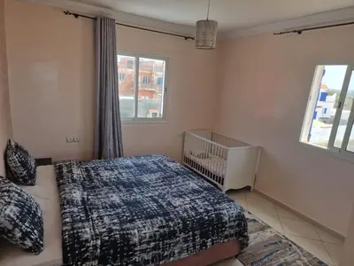 a bedroom with a bed and a crib in it at La petite villa avec piscine pieds dans l'eau in Sidi Rahal