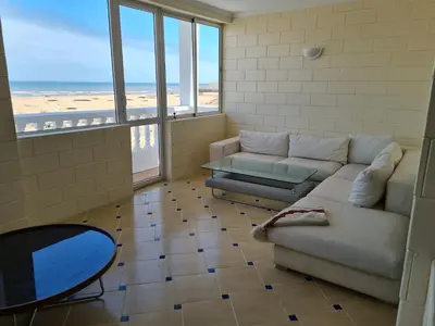 a living room with a couch and a table and windows at La petite villa avec piscine pieds dans l'eau in Sidi Rahal