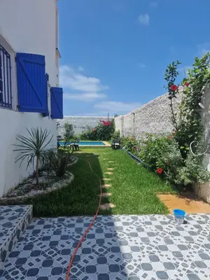 a garden with a hose attached to a building at La petite villa avec piscine pieds dans l'eau in Sidi Rahal