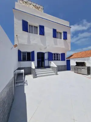 a white house with blue windows and a patio at La petite villa avec piscine pieds dans l'eau in Sidi Rahal