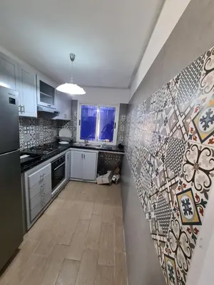 a kitchen with white cabinets and a tile wall at La petite villa avec piscine pieds dans l'eau in Sidi Rahal