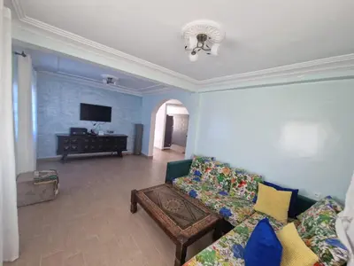 a living room with a couch and a tv at La petite villa avec piscine pieds dans l'eau in Sidi Rahal