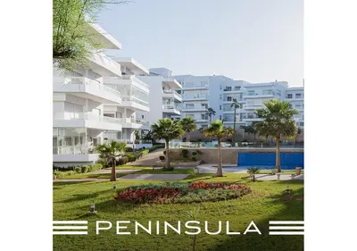 a large white apartment building with palm trees and a park at Peninsula Dar Bouazza Superbe appartement en résidence avec piscine activités in Dar Bouazza