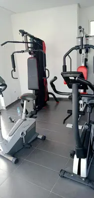 a gym with two exercise bikes and a treadmill at Appartement Familial avec Jardin, Résidence avec Piscine Dar El Bahr in Sidi Rahal