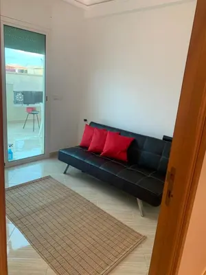 a black couch in a living room with red pillows at A 5 minutes à pied de la plage un bel appartement à saisir in Sidi Rahal