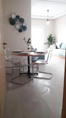 a dining table and chairs in a living room at Appart. Luxueux avec piscine, cosy, bien situé in Bouznika
