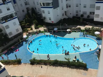 an overhead view of a large swimming pool with people in it at Appart. Luxueux avec piscine, cosy, bien situé in Bouznika