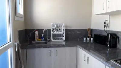 a kitchen counter with a sink and a microwave at Appart. Luxueux avec piscine, cosy, bien situé in Bouznika