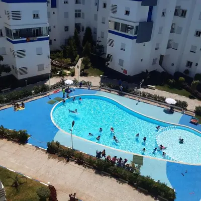 an overhead view of a large swimming pool with people in it at Appart. Luxueux avec piscine, cosy, bien situé in Bouznika