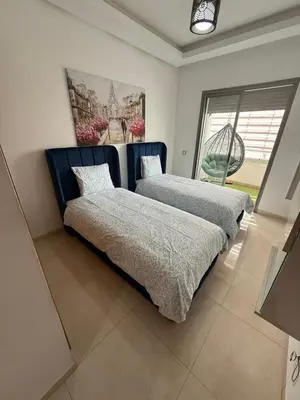a bedroom with two beds and a window at Très bel appartement neuf à Mansbay Manssouria in Mohammedia