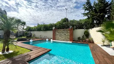 a swimming pool in a backyard with a wooden deck at Lilas Park Villa - Casablanca Bouskoura in Casablanca