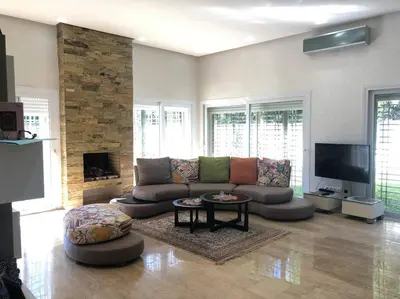 a living room with a couch and a tv at Lilas Park Villa - Casablanca Bouskoura in Casablanca