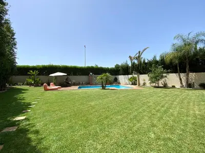 a grassy yard with a swimming pool in a backyard at Lilas Park Villa - Casablanca Bouskoura in Casablanca