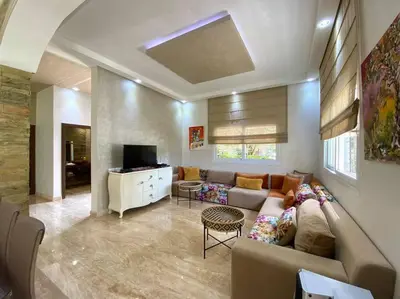 a living room with a couch and a tv at Lilas Park Villa - Casablanca Bouskoura in Casablanca