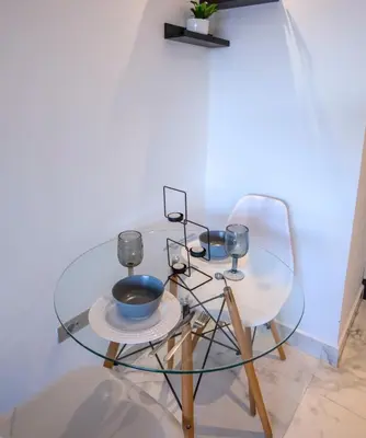 a glass table with two chairs and a bowl and glasses at Appartement chic en plein Gauthier in Casablanca