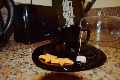 a black cup sitting on a black plate with cookies at CASABAY Sidi Rahal, appartement avec accés direct à la plage et piscine in Sidi Rahal
