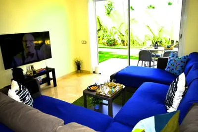 a living room with blue couches and a tv at CASABAY Sidi Rahal, appartement avec accés direct à la plage et piscine in Sidi Rahal