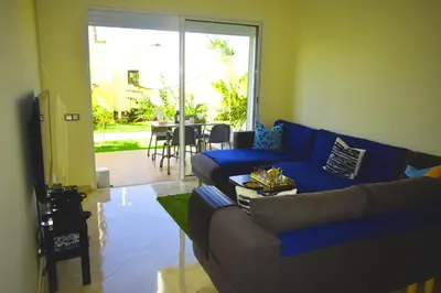 a living room with a blue couch and a table at CASABAY Sidi Rahal, appartement avec accés direct à la plage et piscine in Sidi Rahal