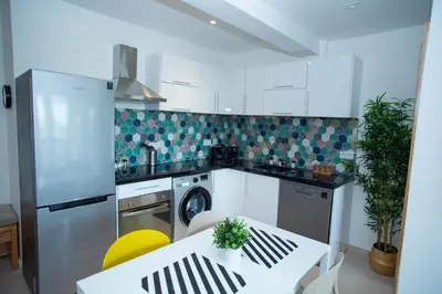 a kitchen with a refrigerator and a table and a dishwasher at My Cosy Place Rabat - Appartements à 50m de la gare Agdal TGV in Rabat