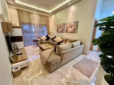 a living room with a couch and a table at Apparemment de luxe vue piscine in Bouznika