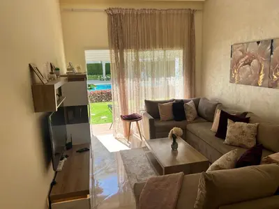 a living room with a couch and a table at Apparemment de luxe vue piscine in Bouznika