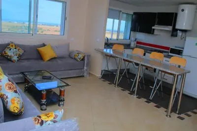 a living room with a couch and a table with chairs at BOUZNIKA Appartement 4 in Bouznika