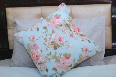a pillow with pink flowers on a bed at Appartement au centre ville in Bouznika