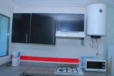 a kitchen with black and white cabinets and a microwave at BOUZNIKA au centre in Bouznika