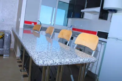 a kitchen with a counter with chairs and a table at BOUZNIKA au centre in Bouznika