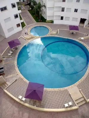 an overhead view of a large swimming pool with umbrellas at Appartement - Bouznika Centre in Bouznika