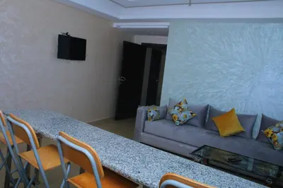 a living room with a couch and a table with chairs at Appartement - Bouznika Centre in Bouznika