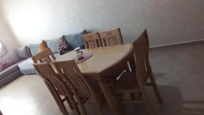 a dining room table with four chairs and a couch at BOUZNIKA Appartement in Bouznika