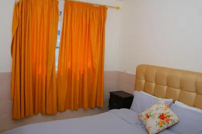 a bedroom with a bed and orange curtains at BOUZNIKA Piscine et plage in Bouznika