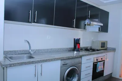 a kitchen with a sink and a washing machine at BOUZNIKA Piscine et plage in Bouznika