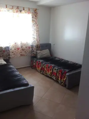 a bed in a room with a window and a couch at Superbe appartement Bouznika in Bouznika