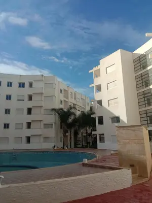 a building with a swimming pool in front of a building at Superbe appartement Bouznika in Bouznika
