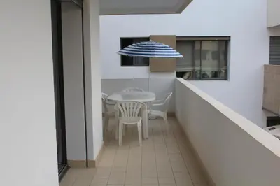 a balcony with a table and a blue and white umbrella at Appartement du bonheur Paradise in Mohammedia