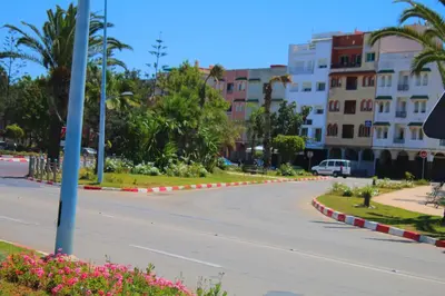 an empty street in a city with palm trees and buildings at Le chant de la rivière BOUZNIKA in Bouznika