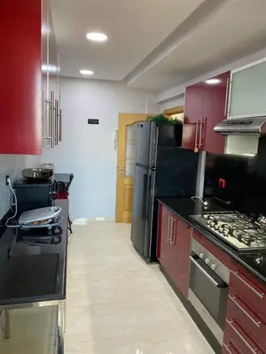 a kitchen with red cabinets and a black refrigerator at Magnifique F3 rénové Fibre, Parking & excellente desserte in Casablanca