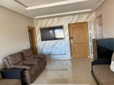 a living room with a couch and a television on a wall at Magnifique F3 rénové Fibre, Parking & excellente desserte in Casablanca