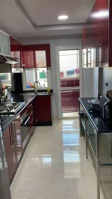 a kitchen with black counter tops and red cabinets at Magnifique F3 rénové Fibre, Parking & excellente desserte in Casablanca